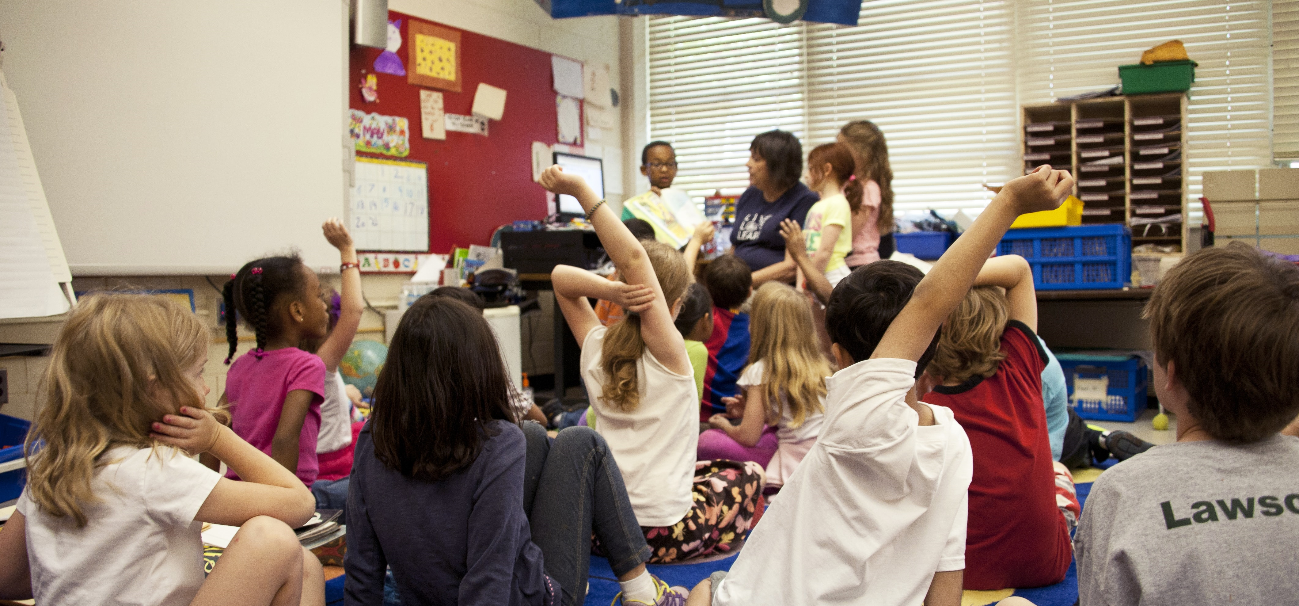 A class of school children hold up their hands