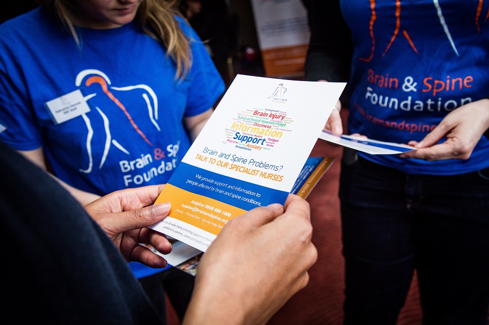 A group of people reading a leaflet about brain and spine problems