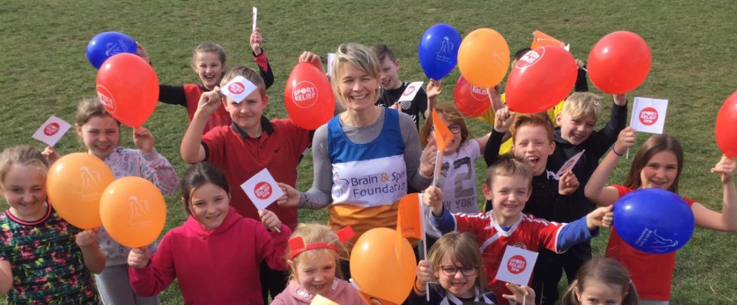 A woman celebrates with a group of children holding balloons